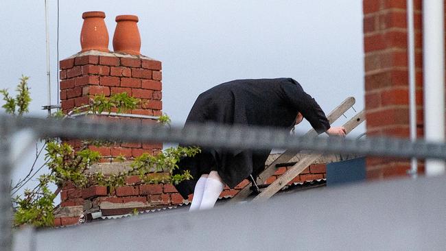 A man climbs across a roof to leave the illegal gathering. Picture: Mark Stewart