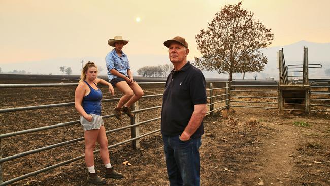 Cattle farmer John McVean with granddaughters Amarnie McVean, left, and Kelsie Lupson in a scorched paddock near Corryong. Picture: Aaron Francis