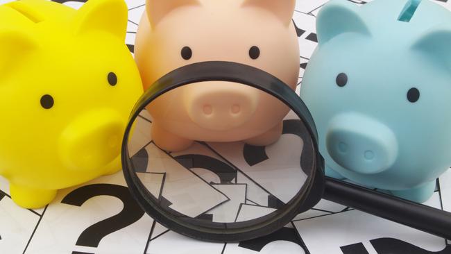 Three piggy banks under magnifying glass on question marks background. Saving money concept; superannuation saving generic