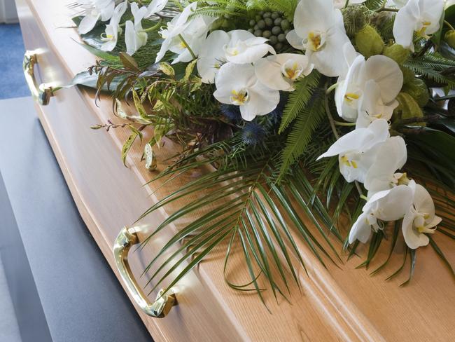 A coffin with a flower arrangement in a morgue