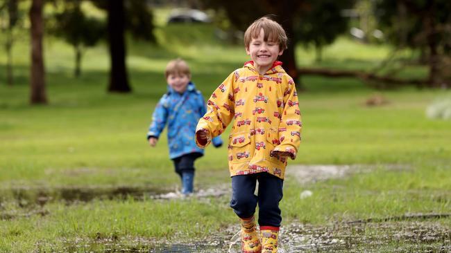 DAILY TELEGRAPH, OCTOBER 9, 2022: Monty wells (4) (yellow jacket right) and Jude Wells (3) pictured walking through a puddle at Centennial Park, Moore Park. Picture: Damian Shaw