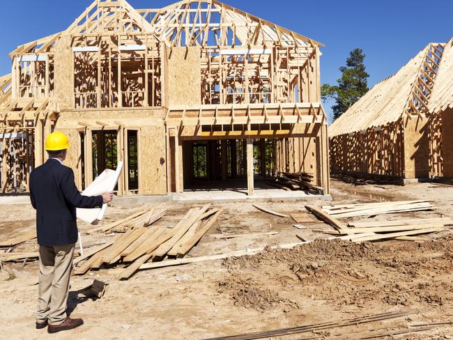 Developing Queensland - New home construction site with contractor in foreground.