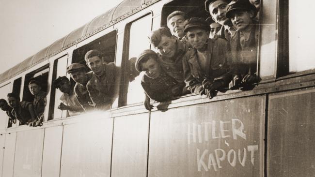Jewish youth liberated at Buchenwald lean out the windows of a train marked with the phrase Hitler kapout in June 1945. Picture: Supplied.