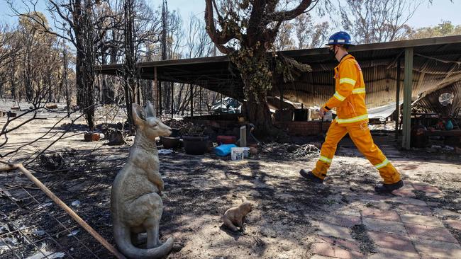 A firefighter passes an ornamental statue of a kangaroo in the yard of a razed house after bushfires in Gidgegannup, 40 kilometres northeast of Perth. Picture: AFP