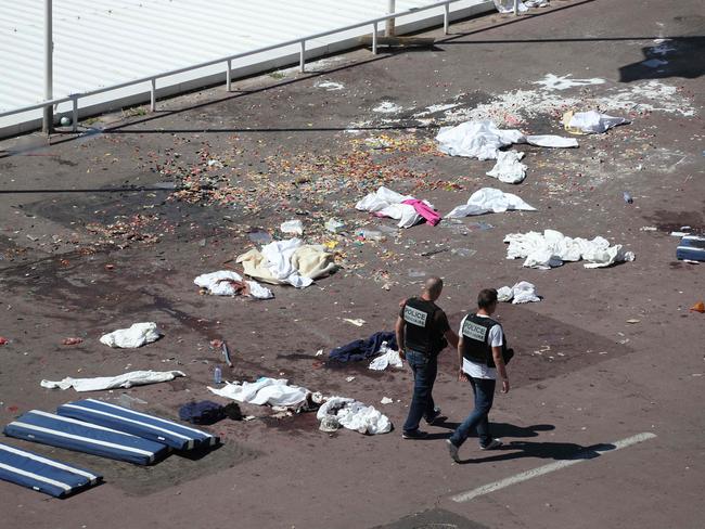 TOPSHOT - Policemen walk on the site where a truck drove into a crowd watching a fireworks display on the Promenade des Anglais seafront in the French Riviera town of Nice on July 15, 2016. An attack in Nice where a man rammed a truck into a crowd of people left 84 dead and another 18 in a 