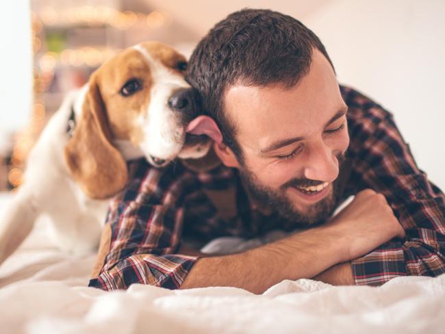 Young smiling man affectionate with his dog  - picture istock