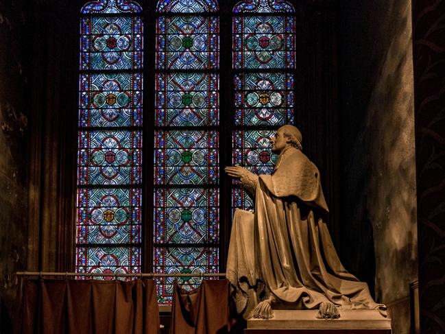 A statue of Archbishop Sibour stands in front of a stunning blue and green stained glass window at Notre-Dame Cathedral , Paris. Picture: Alamy