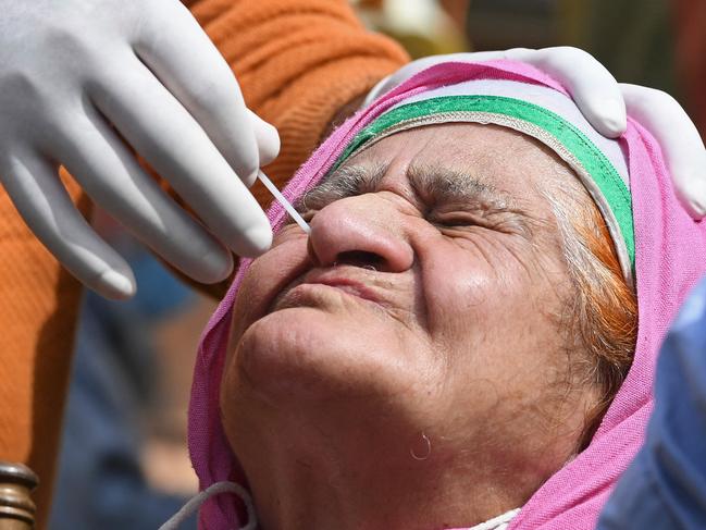 A health worker takes a nasal swab sample from a woman to test for the Covid-19 coronavirus at a testing center in Srinagar on April 21, 2021. (Photo by TAUSEEF MUSTAFA / AFP)