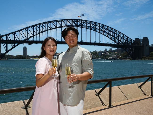 SYDNEY, AUSTRALIA : NewsWire Photos - DECEMBER 23 2024; Korean couple on their honeymoon Selugi Kim and Kyeongwon Lee pose for a photo at the Opera House forecourt with a view of the Sydney Harbour Bridge in the background as new tourism data for NSW is released. Picture: NewsWire/ Gaye Gerard