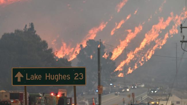 Flames from the Hughes Fire burn a hillside in Castaic, a northwestern part of Los Angeles County, California, on January 22, 2025. A new wildfire erupted north of Los Angeles on January 22, exploding in size and sparking thousands of evacuation orders in a region already staggering from the effects of huge blazes. Ferocious flames were devouring hillsides near Castaic Lake, spreading rapidly to cover 5,000 acres (2,000 hectares) in just over two hours. The fire was being fanned by strong, dry Santa Ana winds that were racing through the area, pushing a vast pall of smoke and embers ahead of the flames. Evacuations were ordered for 19,000 people all around the lake, which sits around 35 miles north of Los Angeles, and close to the city of Santa Clarita. (Photo by Robyn Beck / AFP)