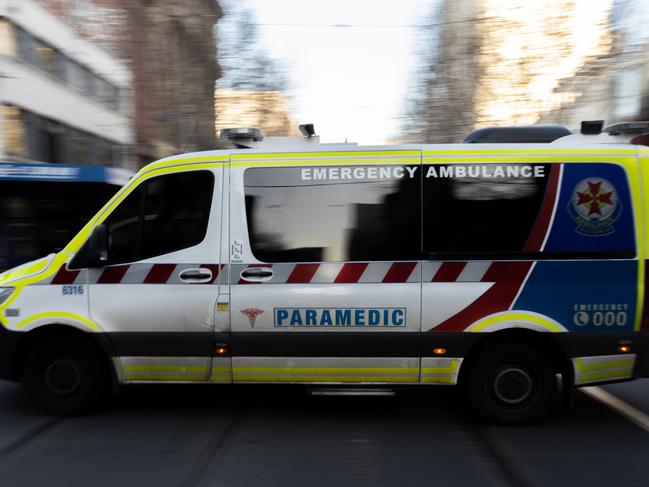 MELBOURNE, AUSTRALIA - JULY 21: An ambulance drives through the CBD on July 21, 2022 in Melbourne, Australia. Victoria recorded 14,312 official cases of COVID-19 in the last 24-hour reporting period, with 875 people hospitalised with the virus, including 46 in intensive care. 37 deaths were also included in this reporting period. While the Federal government has not implemented any COVID-19 restrictions in response to the latest COVID-19 wave, concerns over rising cases of the Omicron subvariants across Australia have seen health authorities recommend the use of face masks indoors, and for people to work from home where possible. (Photo by Asanka Ratnayake/Getty Images)