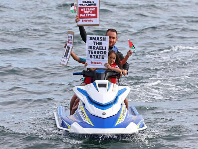 Members of the Australian Palestinian community hold placards as they sit on a jet ski during a protest at the Port Botany terminal in Sydney on November 21, 2023. Thousands of civilians, both Palestinians and Israelis, have died since October 7, 2023, after Palestinian Hamas militants based in the Gaza Strip entered southern Israel in an unprecedented attack triggering a war declared by Israel on Hamas with retaliatory bombings on Gaza. (Photo by DAVID GRAY / AFP)