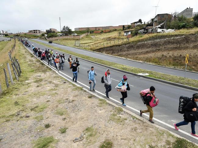 Venezuelan migrants heading to Peru walk along the Panamerican highway in Tulcan, Ecuador, after crossing from Colombia, on August 21, 2018. - Ecuador announced on August 16 that Venezuelans entering the country would need to show passports from August 18 onwards, a document many are not carrying. And Peru followed suit on August 17, announcing an identical measure due to begin on August 25. (Photo by Luis ROBAYO / AFP)