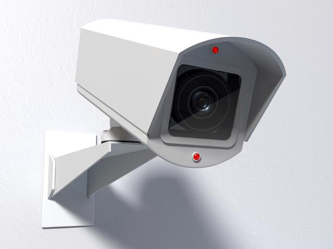 A white wireless surveillance camera with illuminated lights mounted on an isolated white wall with copy space