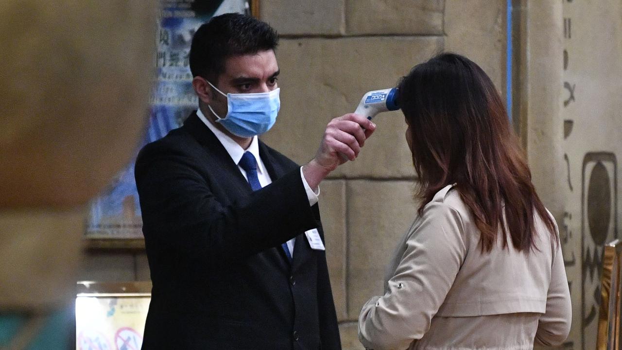 A staff member checks the temperature of a guest entering a hotel in Macau on January 22, 2020. Picture: Anthony Wallace/AFP