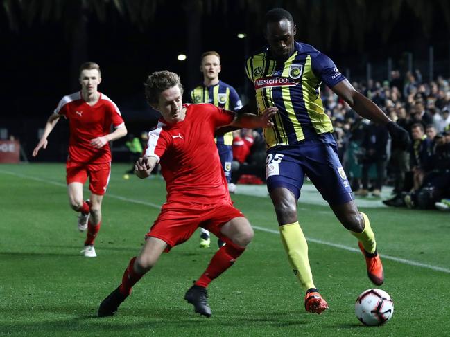 Olympic sprinter Usain Bolt, playing for A-League football club Central Coast Mariners, fights for the ball with a player from a  a Central Coast amateur selection team during a pre-season practice football match in Gosford, New South Wales on August 31, 2018. - Sprint king Usain Bolt made his much-anticipated football debut on August 31, exciting fans but tiring quickly in a 20-minute cameo as his Central Coast Mariners hammered an amateur side 6-1 in a pre-season warm-up. (Photo by Andrew Murray / AFP) / -- IMAGE RESTRICTED TO EDITORIAL USE - STRICTLY NO COMMERCIAL USE --