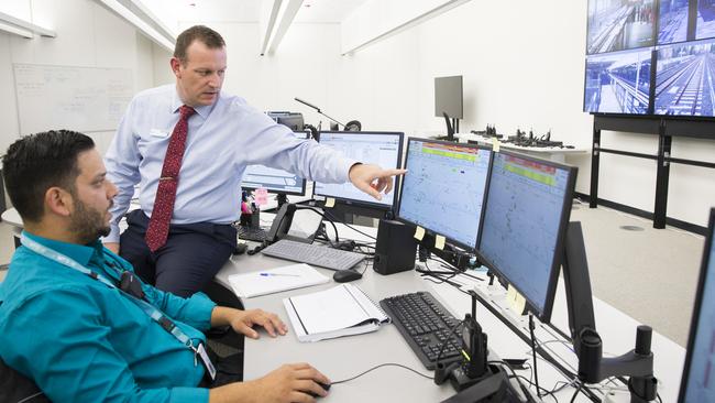 Cory Roeten, who runs the Operations Control Centre for driverless trains, speaking with traffic controller Heinz Bastiampillai. Picture: Dylan Robinson