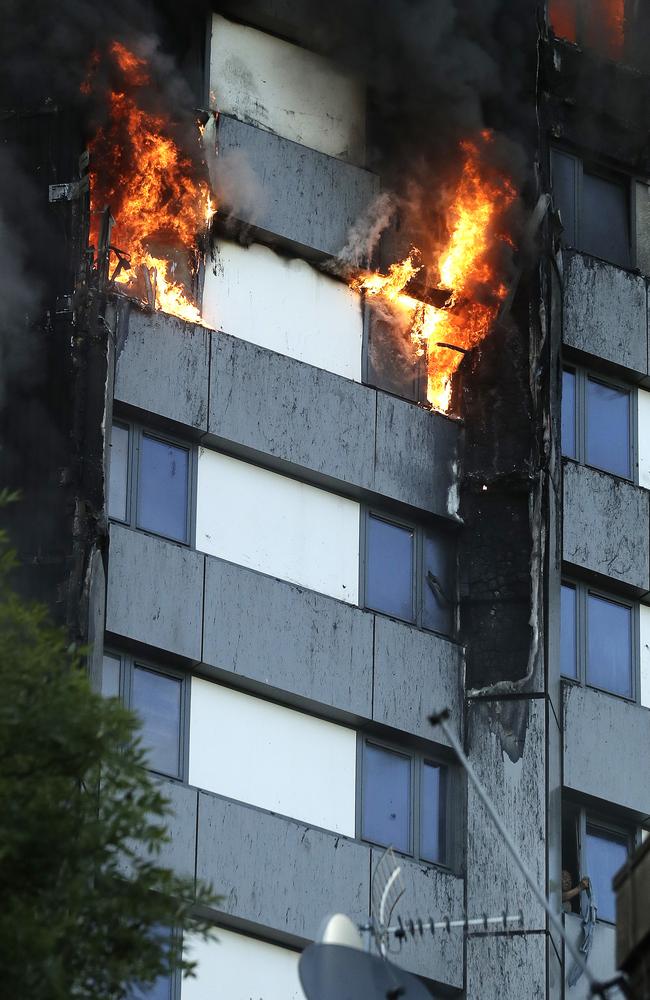 A resident, bottom right, peers out of a window from the building apartment block. Picture: AP