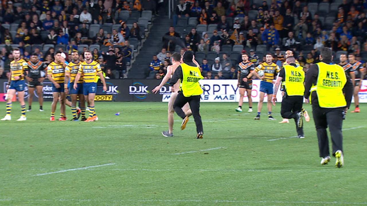 A cheeky streaker gets up close and personal with players during the Eels and Tigers clash.