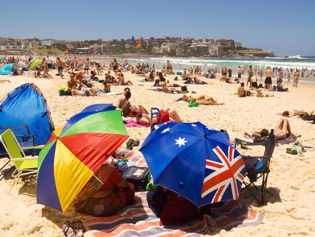 Sydney, Australia - December 31, 2013: Colourful umbrellas, tents, chairs and towels shade some beachgoers from the sun on New Year's Eve at Bondi Beach.