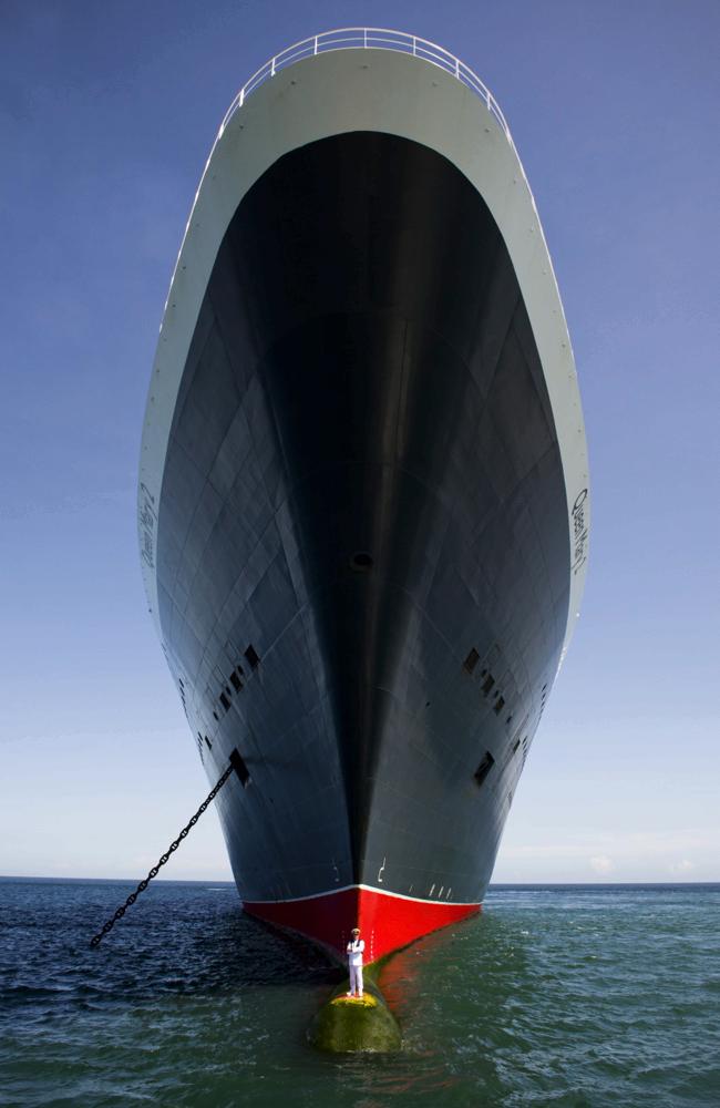 Captain Kevin Oprey stands beneath the soaring hull of the QM2. Picture: James Morgan