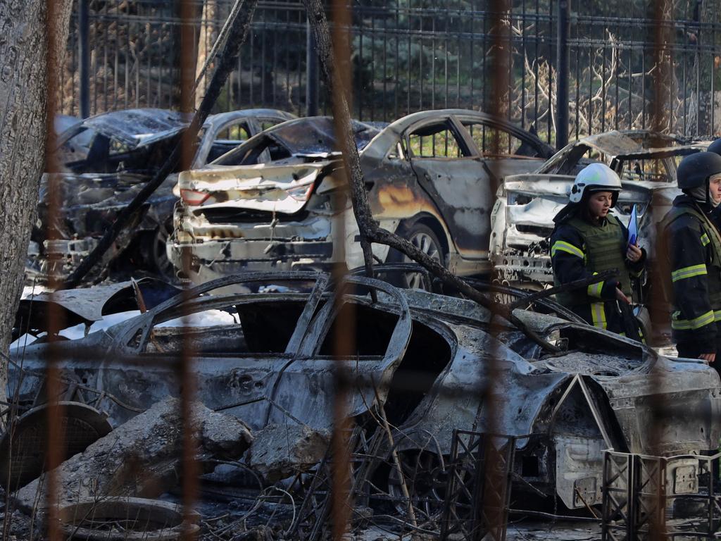 Ukrainian rescuers stand among burnt-out cars in the courtyard of a residential building following a missile attack in Odessa. Picture: AFP