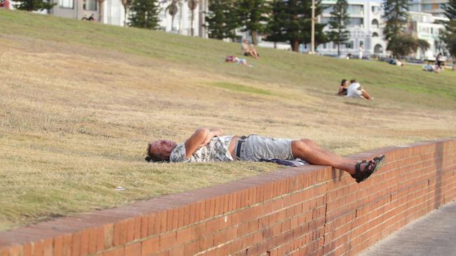 A man takes in the new year by sprawling out on the grass at Bondi. Picture: NewsWire / Christian Gilles