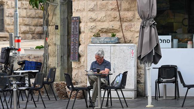 A man reads at a cafe in Jerusalem on April 14, 2024. Iran's unprecedented attack on Israel has been "foiled," the Israeli army announced on April 14, with almost all of the more than 200 missiles and drones intercepted with the help of the United States and allies. (Photo by Ronaldo SCHEMIDT / AFP)