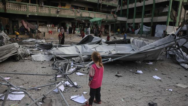 A Palestinian girl watches as others clear debris and rubble at the Fatima Bint Asad school hit in overnight Israeli strikes in Jabalia in the northern Gaza Strip on Monday. Picture: AFP