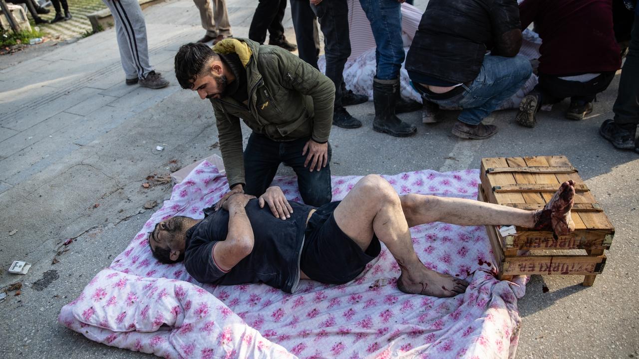 A wounded survivor lies on the ground at the site of a collapsed building in Hatay, Turkey. (Photo by Burak Kara/Getty Images)