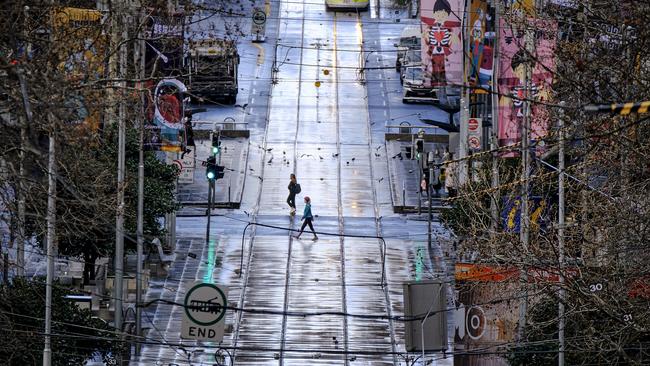 People commute on an empty street in Melbourne as the city endures another marathon lockdown. Picture: Luis Ascui