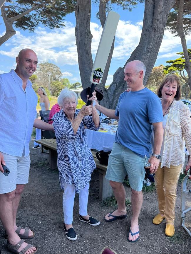 Eileen Nation raises the bat for her century of birthdays with grandson Jackson (left) and Lucas Wilson, alongside her daughter, Lyn Wilson. Photo: Supplied.