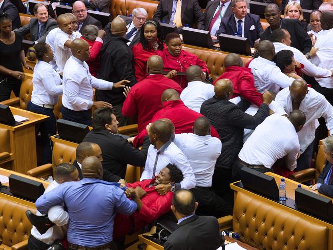 Economic Freedom Fighters (EFF, in red) party members of parliament are physically removed from the South African parliament. Picture: AFP