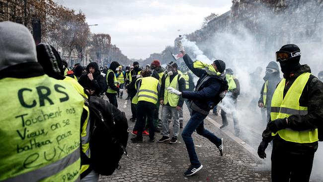 So-called “yellow vests”, or “gilets jaunes” hurl back tear gas canisters during clashes with police in Paris. Pioc: AFP