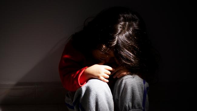 young girl sitting down alone in the dark.