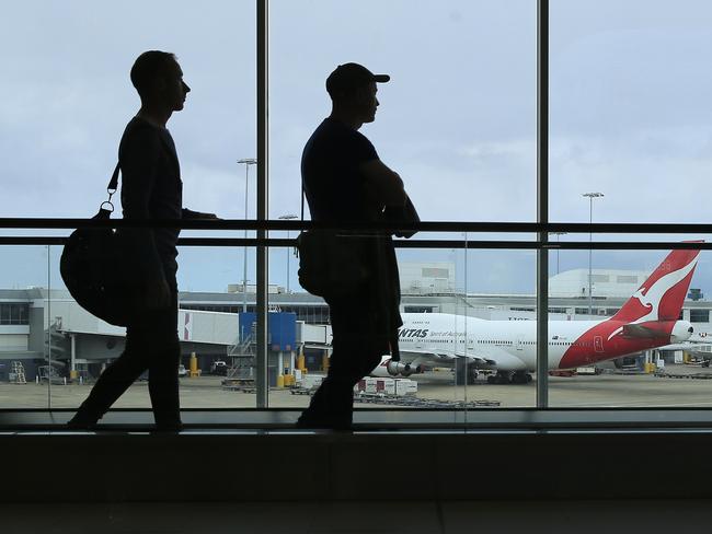 SYDNEY, AUSTRALIA - MARCH 10: Two passengers walk past a Qantas jet at the International terminal at Sydney Airport on March 10, 2020 in Sydney, Australia. Qantas has cut almost a quarter of its international capacity for the next six months as travel demands fall due to fears over COVID-19. The airline today announced it was altering routes to London and would be parking eight of their 12 A380 aircraft. (Photo by Mark Evans/Getty Images)