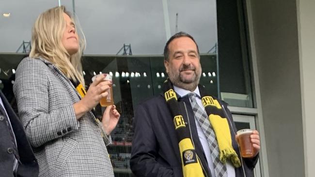 Mick Molloy enjoying a beer with his partner at the footy.