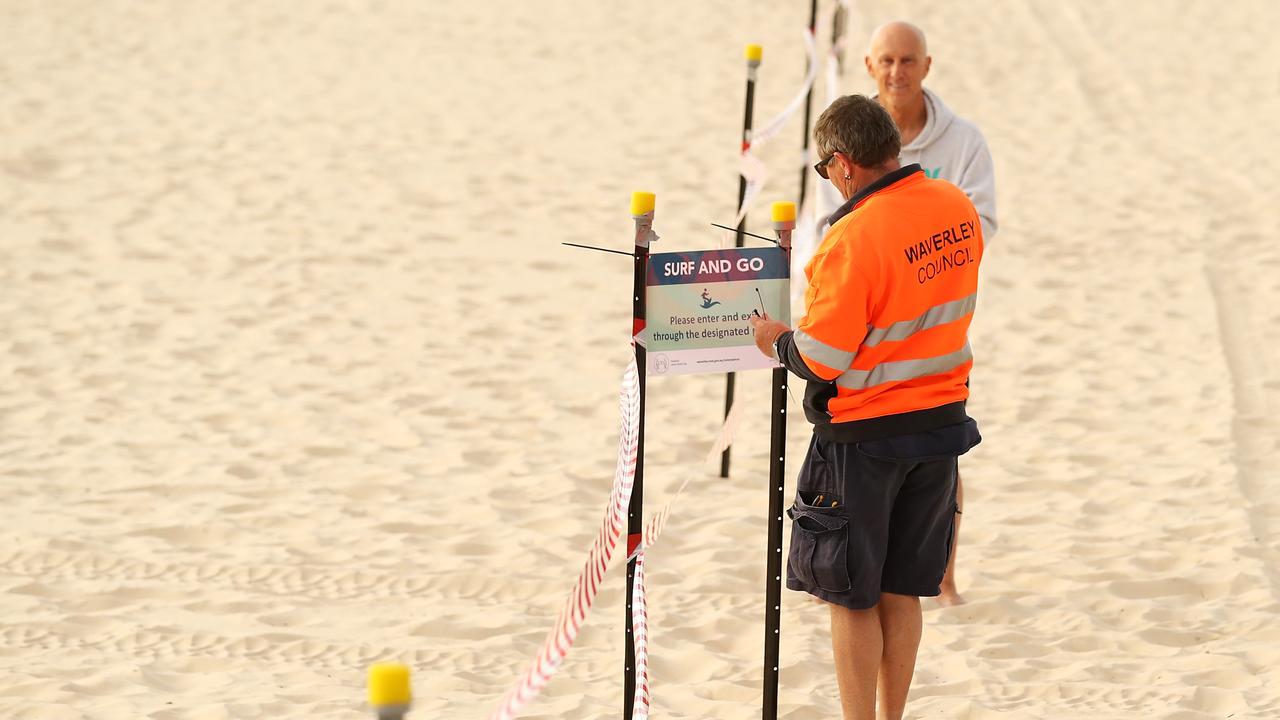 A council worker puts up a sign on the beach walkway before the reopening of Bondi Beach this morning. Picture: Mark Kolbe/Getty Images