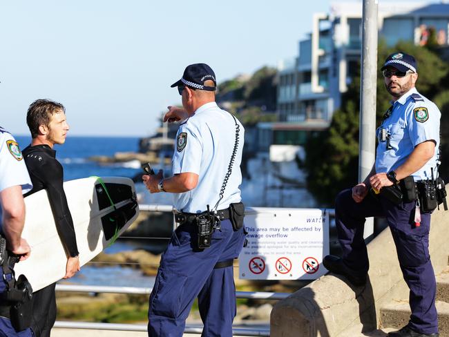 A lone surfer is found surfing out the back of Bondi Beach greeted by the Police as he came in to shore in Bondi, Sydney, April 25 2020. Picture: Gaye Gerard/ Sunday Telegraph