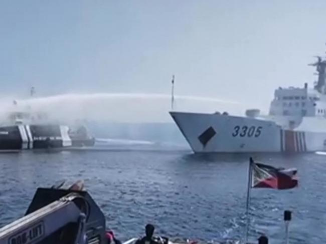 This frame grab taken from video footage released by the Philippine Coast Guard (PCG) via AFPTV on December 9, 2023 shows a Chinese Coast Guard ship (R) using a water cannon on a Philippine Bureau of Fisheries and Aquatic Resources (BFAR) vessel near Scarborough Shoal in the disputed South China Sea. The Philippines accused the Chinese coast guard on December 9 of using water cannons to "obstruct" three government boats delivering provisions to Filipino fishermen near a China-controlled reef in the South China Sea. (Photo by Handout / Philippine Coast Guard (PCG) / AFP) / RESTRICTED TO EDITORIAL USE - MANDATORY CREDIT "AFP PHOTO /  Philippine Coast Guard (PCG) " - NO MARKETING NO ADVERTISING CAMPAIGNS - DISTRIBUTED AS A SERVICE TO CLIENTS