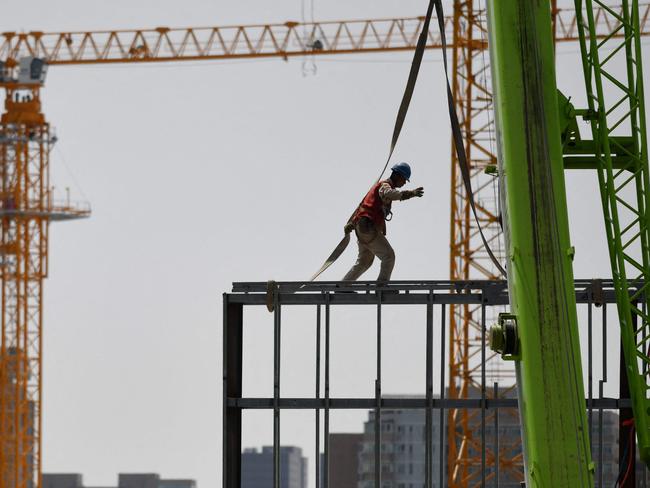 A worker walks on a steel structure at a construction site in Beijing on May 8, 2021. (Photo by GREG BAKER / AFP)