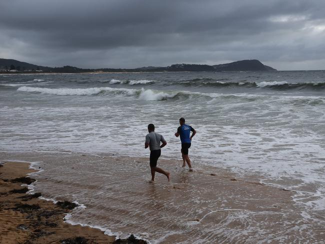 Joggers at Terrigal Beach on Tuesday morning, as a rough surf warning is issued for NSW’s coastline from Grafton down to the Melbourne border. Picture: David Swift