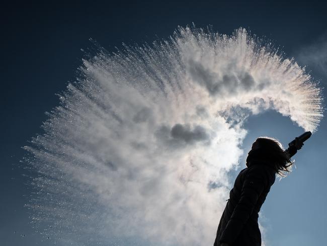 A woman tosses hot water into the freezing cold air that is immediatly turned into a sparkling cloud of snow on March 1, 2018 in Berlin. / AFP PHOTO / dpa / Paul Zinken / Germany OUT