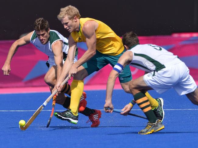 South African defender Lloyd Madsen (left) and Austin Smith (right) attempt to block Australia's hockey team's midfielder Matthew Butturini during the preliminary round men's field hockey match of the London 2012 Olympic Games between Australia and South Africa in London on July 30, 2012. AFP PHOTO/ INDRANILMUKHERJEE