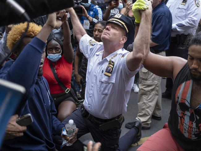 NYPD chief holds hands with protesters while kneeling on the ground. Picture: AP