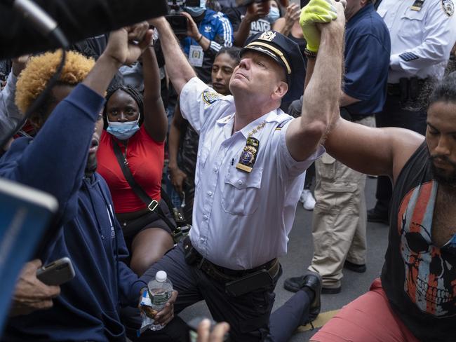 NYPD chief holds hands with protesters while kneeling on the ground. Picture: AP