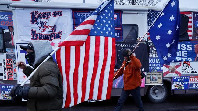 Donald Trump supporters walk past an RV covered in campaign signs, flags and other symbols in New Hampshire. Picture: Getty Images