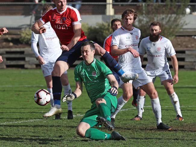 NPL South Hobart vs. Glenorchy Knights, South Hobart Oval: South Hobart's Nicholas Morton (in air) jumps out of the path of Glenorchy goal keeper Dmitri Nester. Picture: LUKE BOWDEN