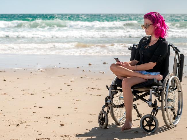 Disabled woman using mobile phone at the beach on a bright day