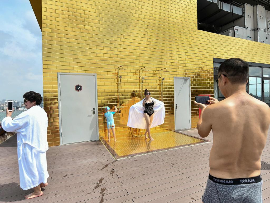 Guests pose for photos against a gold-plated wall near the pool. Picture: Manan Vatsyayana/AFP